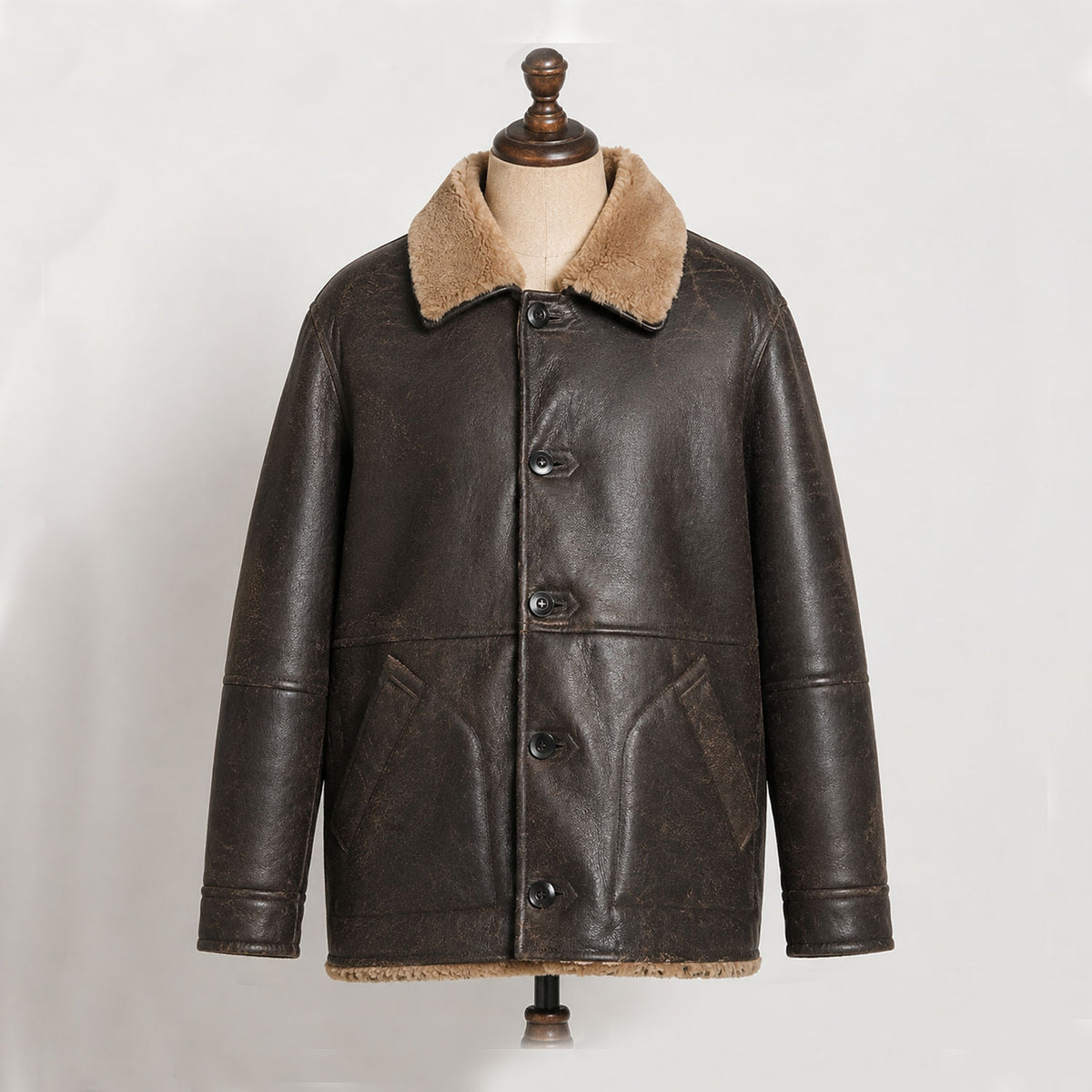 Full product view of men's brown cowhide leather shearling jacket styled as a vintage winter aviator coat, highlighting its rugged leather exterior, faux-fur lining, plush collar, button closure, and classic retro silhouette