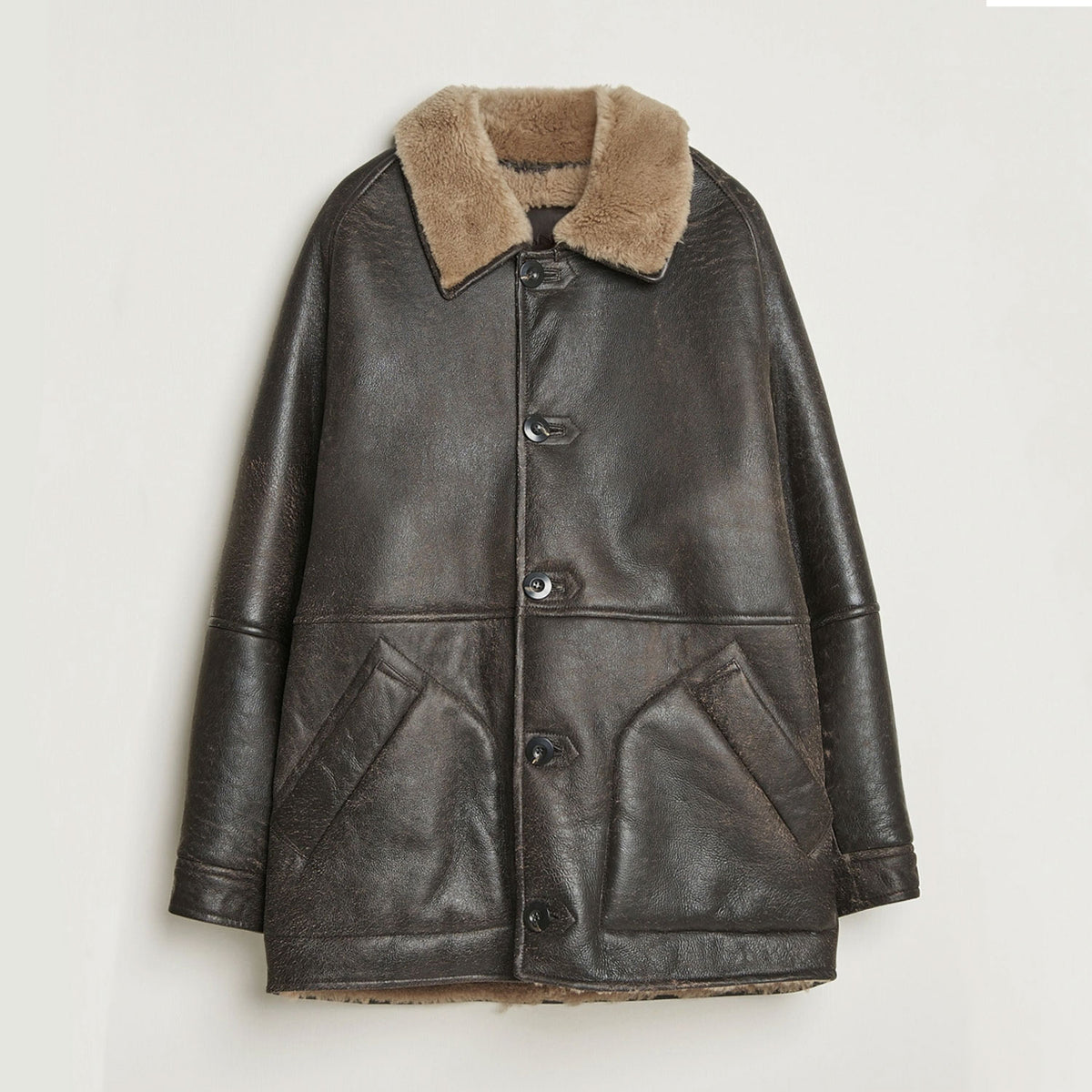 Front view of vintage brown cowhide leather shearling winter jacket with plush faux-fur collar, button-front closure, structured silhouette, and two angled front pockets displayed against a clean studio background